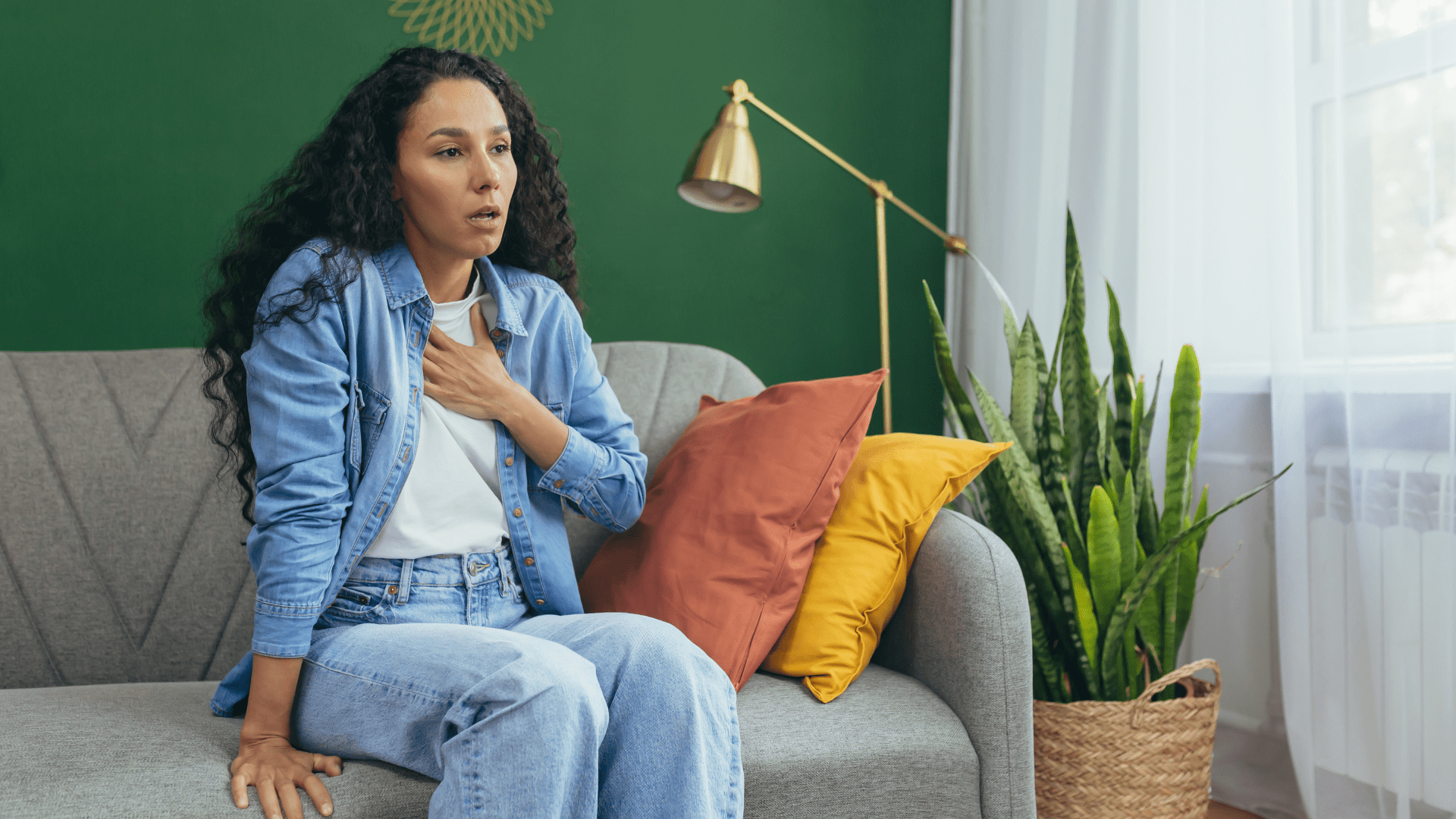 Une personne assise sur un canapé montrant des signes de stress et d'anxiété, représentant une crise d’angoisse ou crise de panique, avec une atmosphère apaisante en arrière-plan.