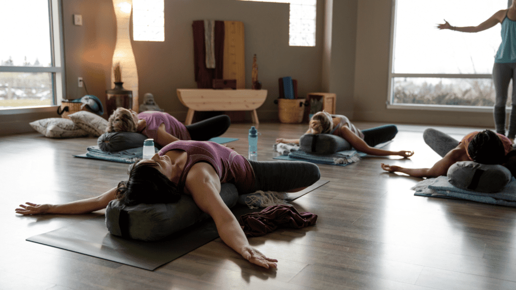 Un groupe de personnes pratiquant le yoga autour de moi dans un studio chaleureux en France.